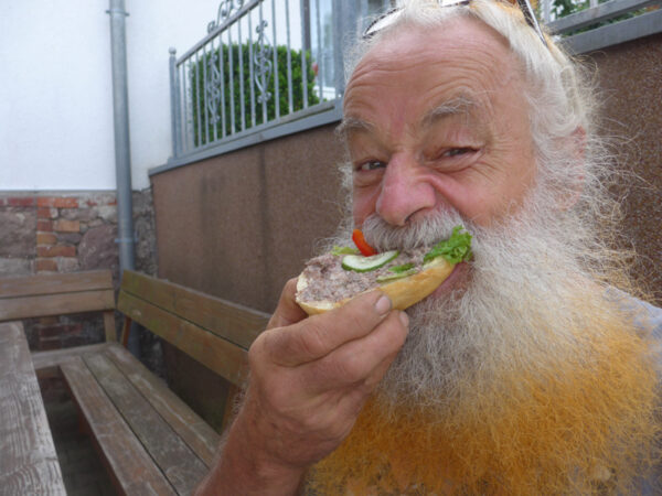 Bärtiger Mann beißt in halbes Brötchen