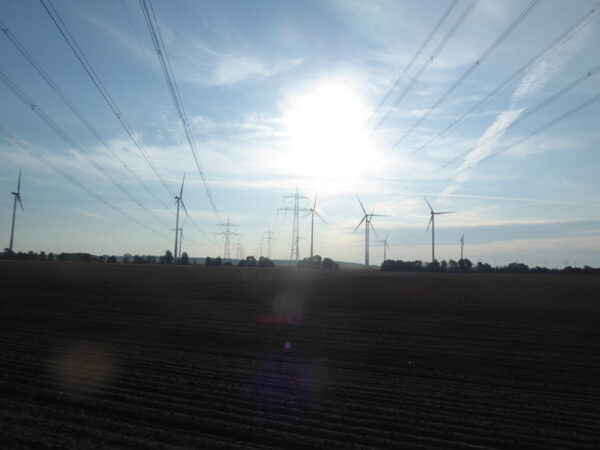 Stromleitungen und Windräder vor den Toren Berlins in aufgehender Sonne