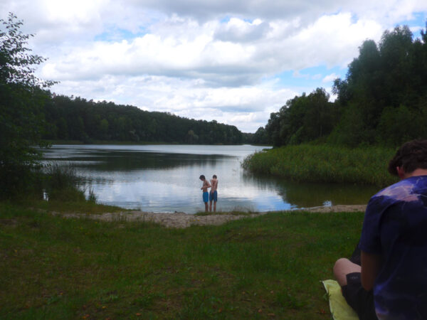 Blick über den Gamensee von seiner Südspitze aus; zwei Jungs stehen am Ufer