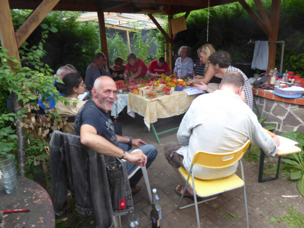 Menschen, die sich um einen Tisch voller Tomaten versammelt haben